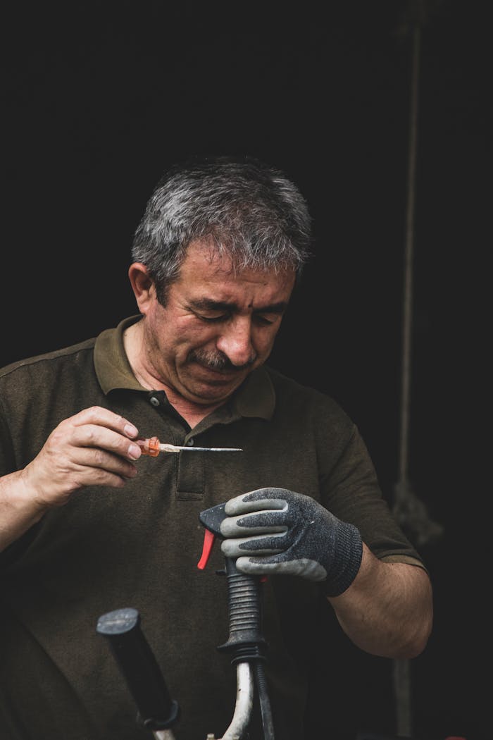 A senior artisan focused on repairing a tool, demonstrating craftsmanship and attention to detail.